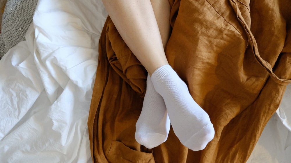 Women's legs in white socks on the bed