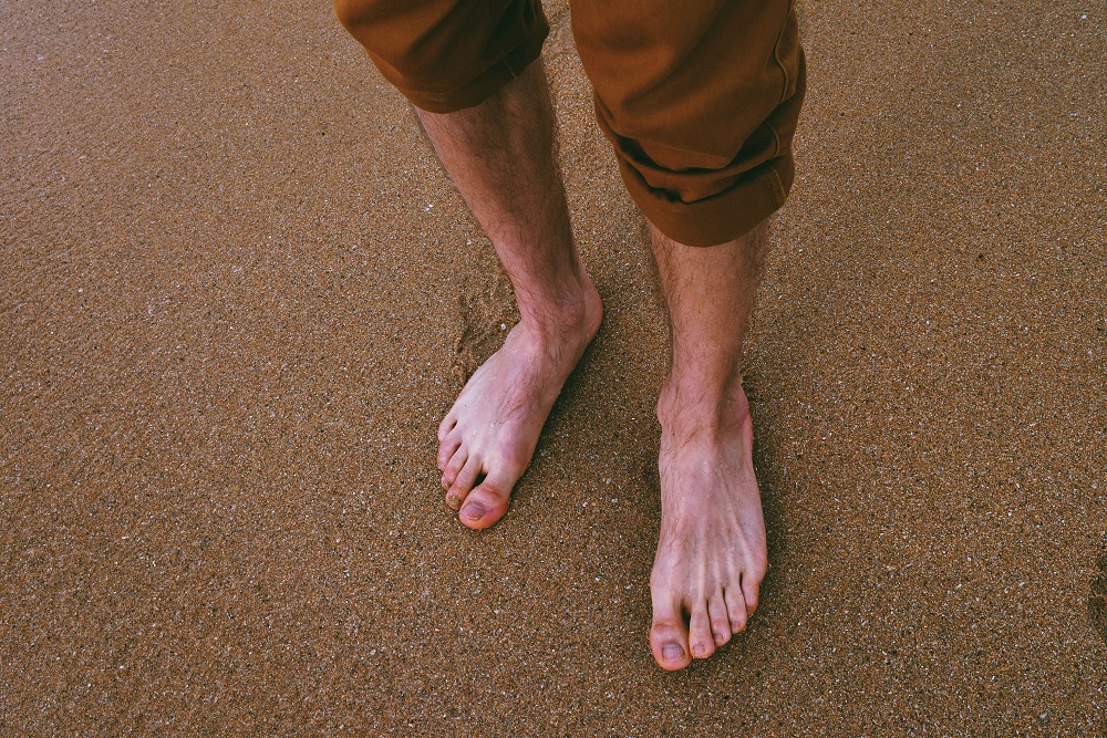 Man standing barefoot on the sand beach
