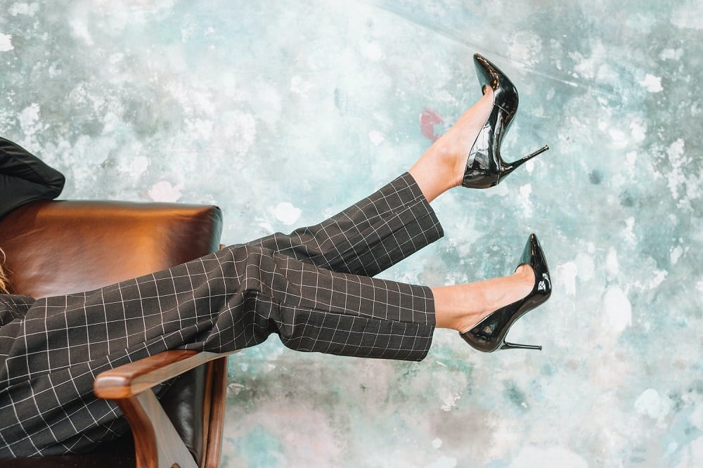 Woman in high heels sitting on a leather chair with legs in the air