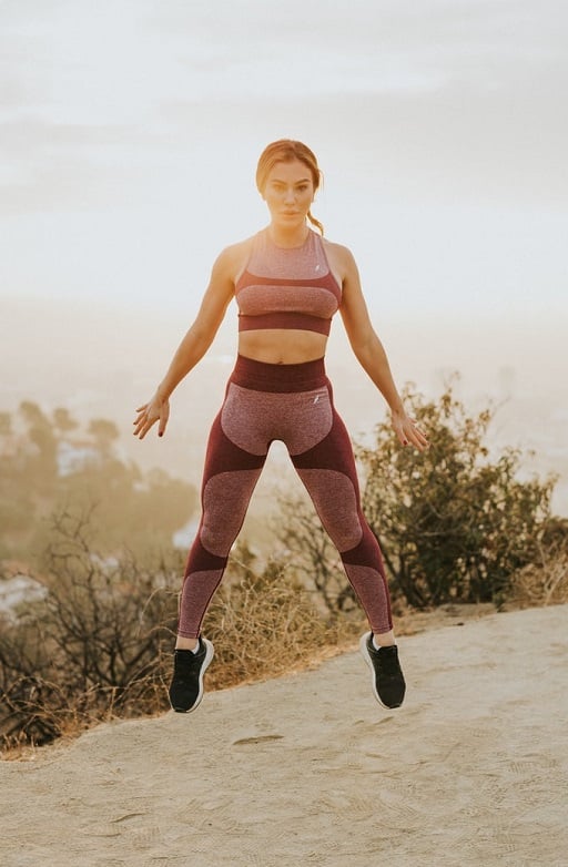 Athletic woman in sporty outfit with tennis shoes, jumping in the air