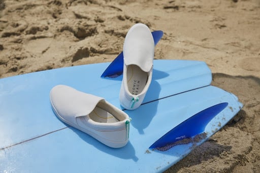 Surfing board and shoes on the sandy beach