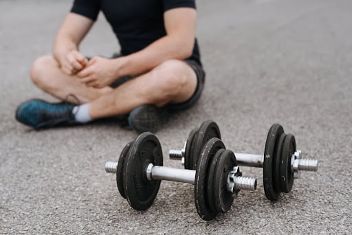 Man sitting on the floor, resting after lifting free weights