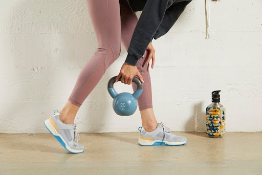 Woman exercising with a dumbell in sporting shoes